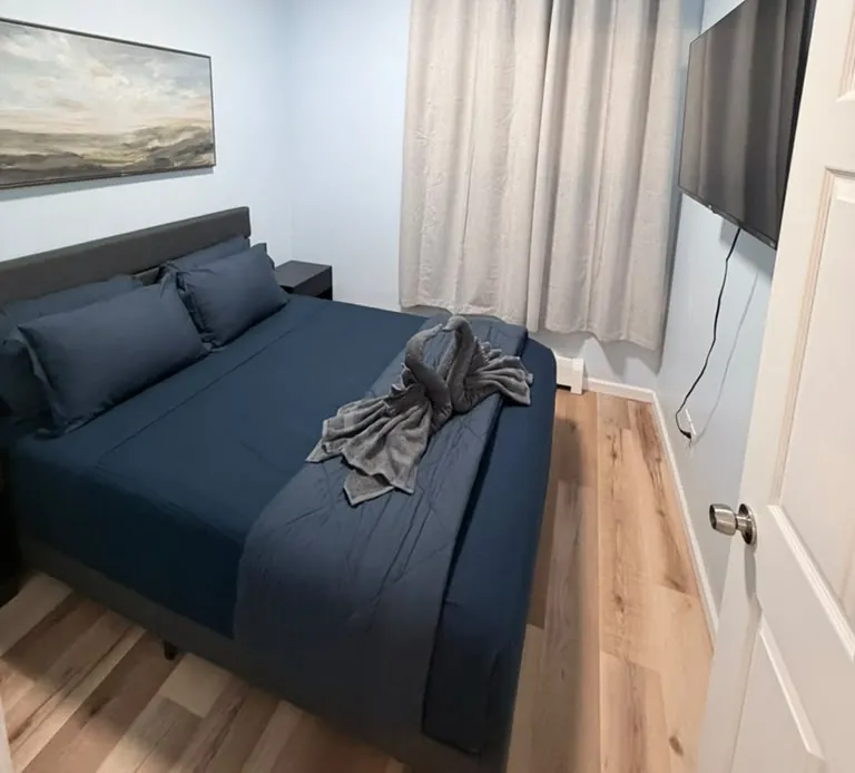 Guest bedroom with navy bedding and folded towel swan after cleaning