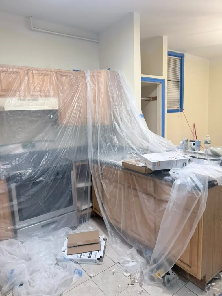 Kitchen cabinets and appliances fully masked with plastic before interior painting