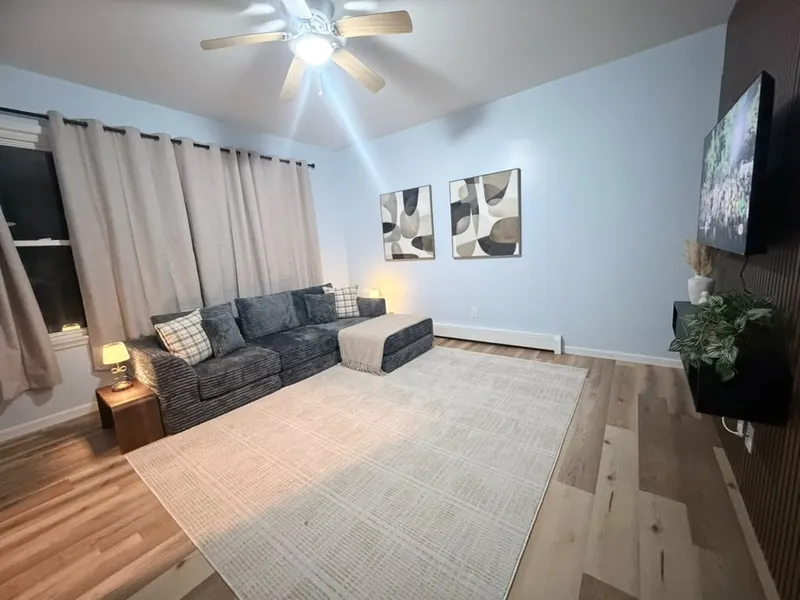 Clean living room with gray sectional, area rug and ceiling fan