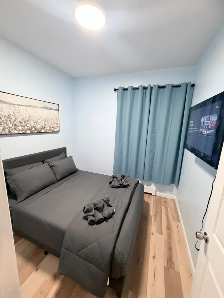 Compact guest bedroom with gray bedding and folded towel animals after a turnover cleaning
